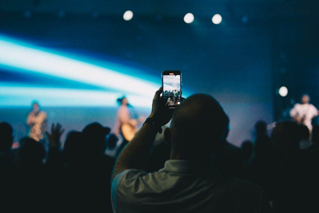 A person taking a picture of a concert with a cell phone